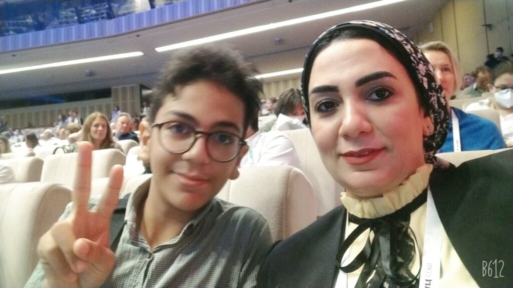 Nevine and her son sitting in a lecture theatre.