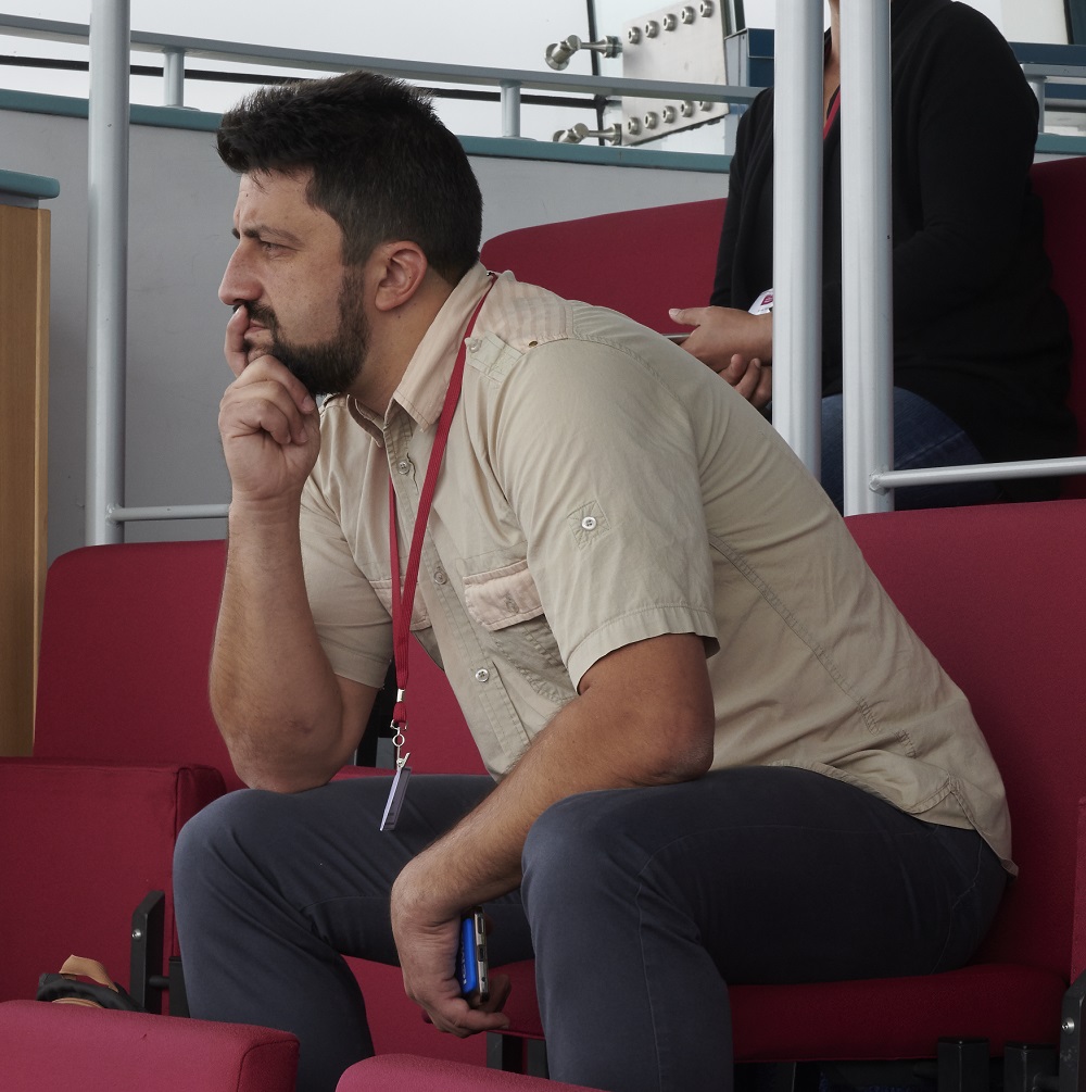 Ciprian sitting on a red bench with his right hand resting under his chin