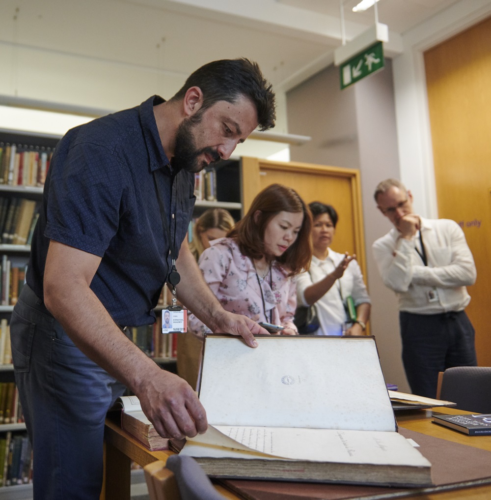 Ciprian turning the page of a large book in the British Museum Anthropology library