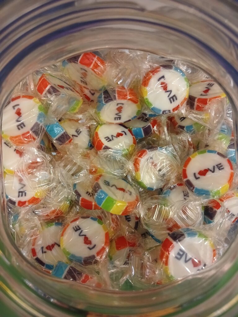 A bowl of sweets which say 'love' with a rainbow pride boarder.