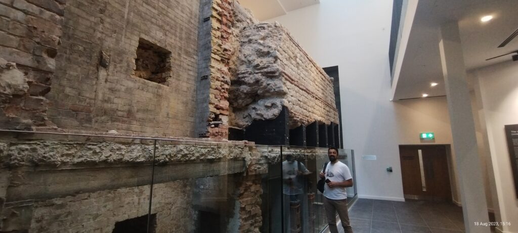 Ciprian standing in front of the Roman wall in the City Wall museum.