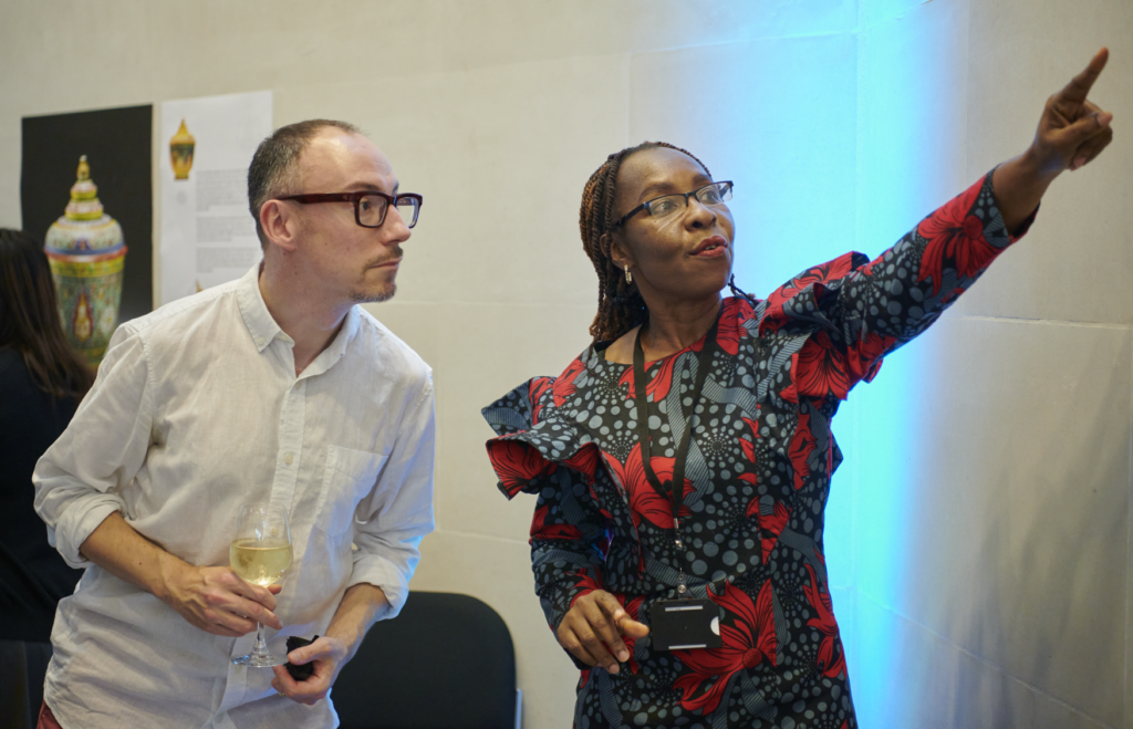 ITP fellow Ogechukwu Okpalanozie points to part of her object in focus display. ITP UK partner Campbell Price stands and listens.