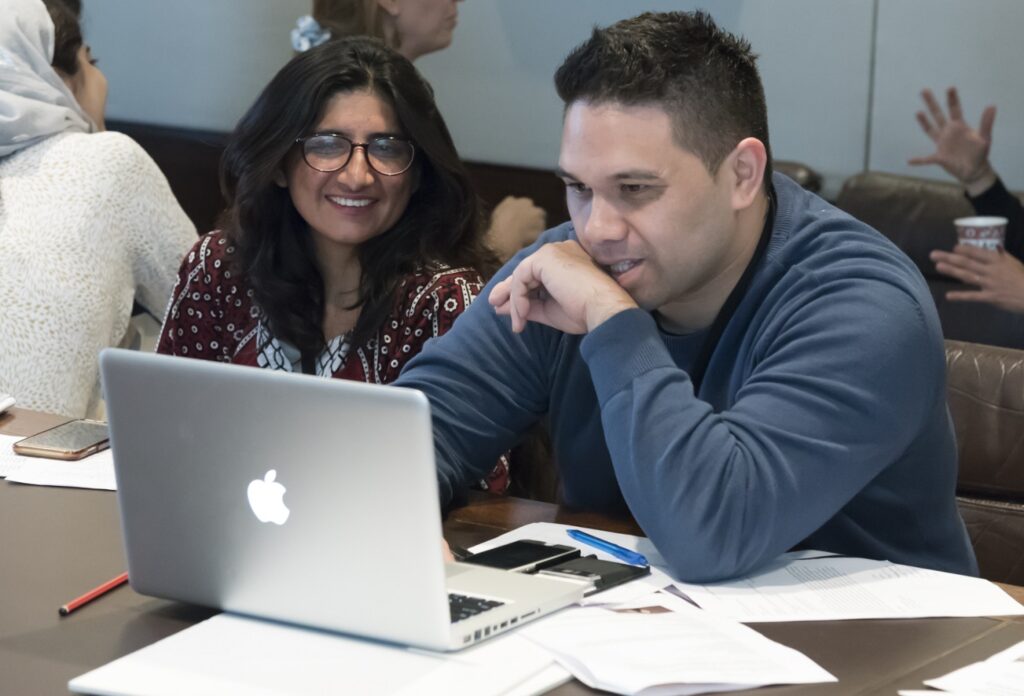 Qurat smiling looking at a computer with another ITP fellow during the 2017 summer programme.