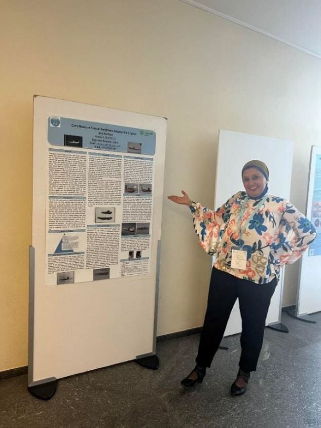 Marwa standing next to a board displaying her research. 