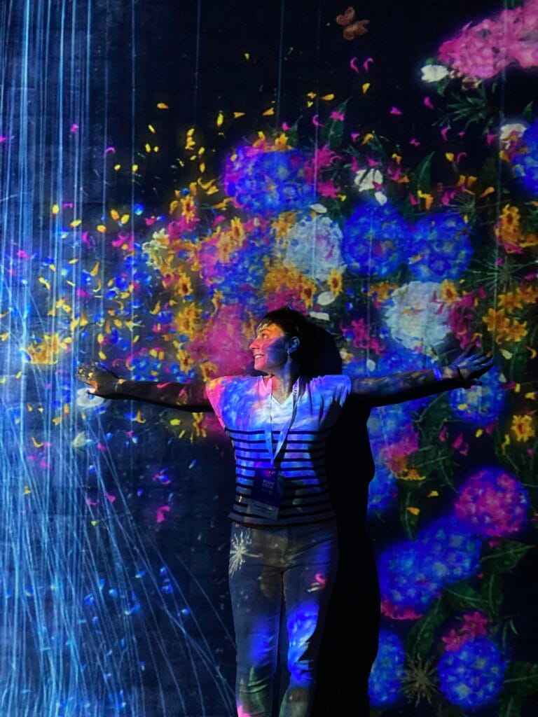 Rema standing in front of a brightly coloured projection at the Art Science Museum in Singapore.