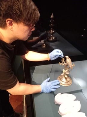 Photograph of a man placing an object on display.
