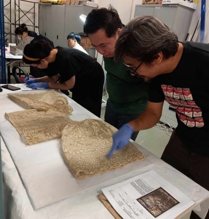 Three people inspecting a textile garment. 