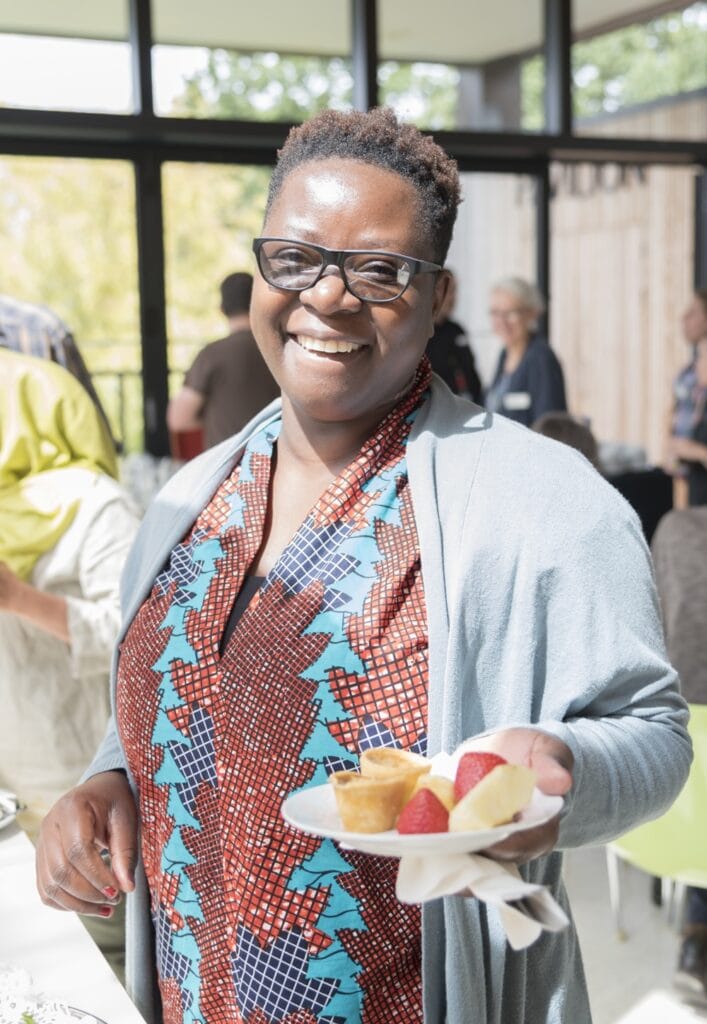 A woman smiling, holding a plate of fruit.